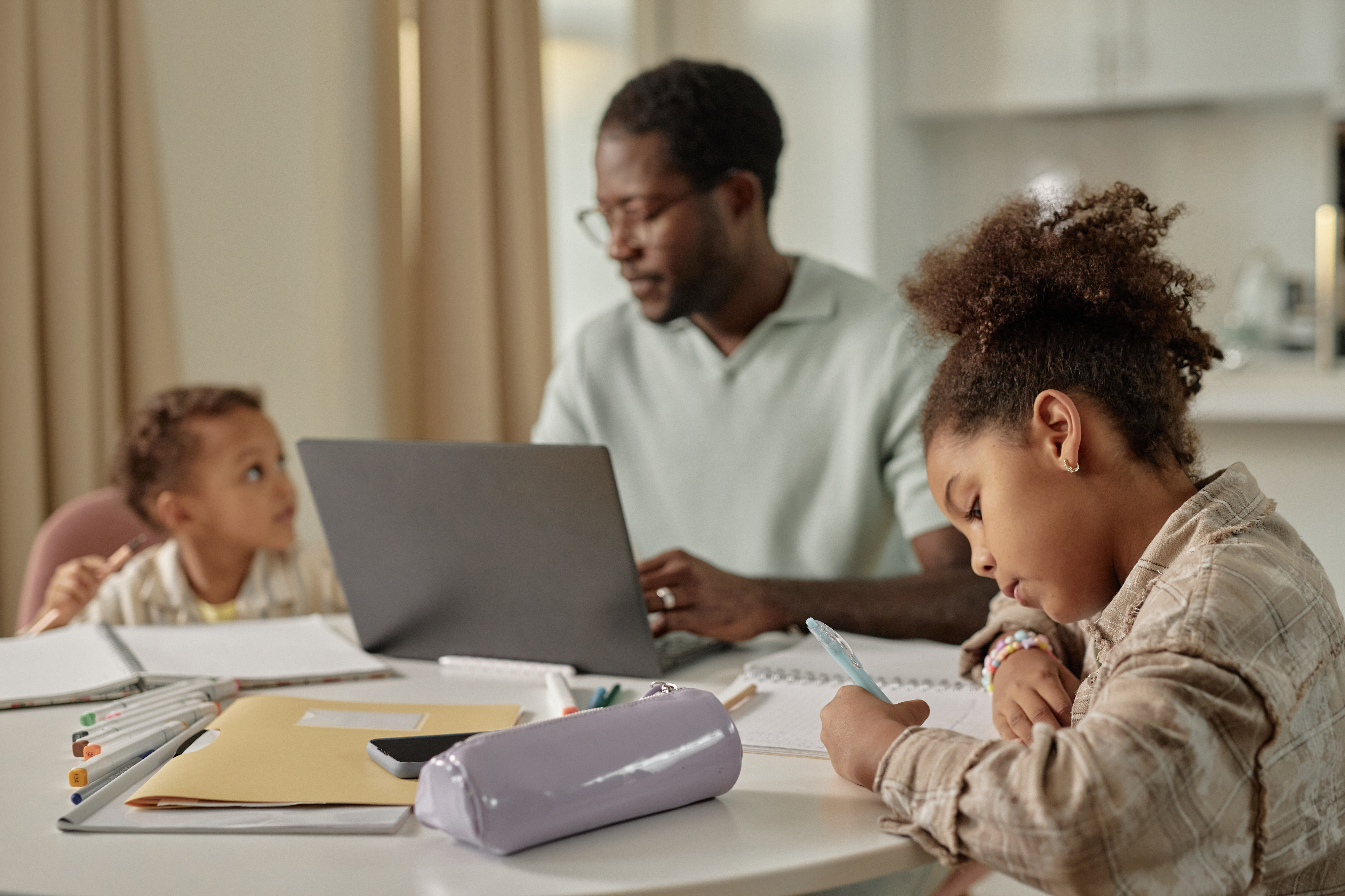 A man with his family at the dining table with a laptop
