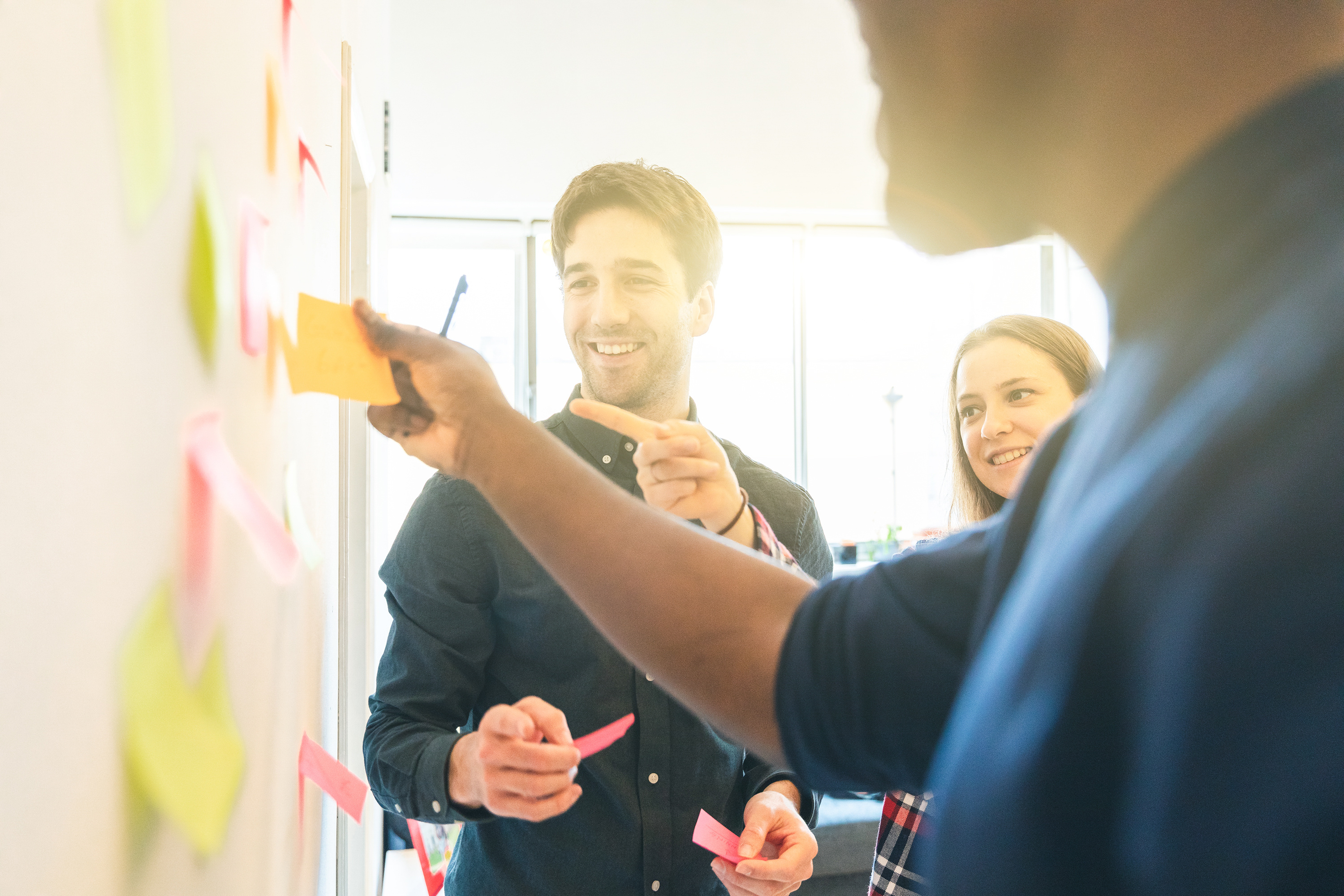 Team members gathering round notes on a wall