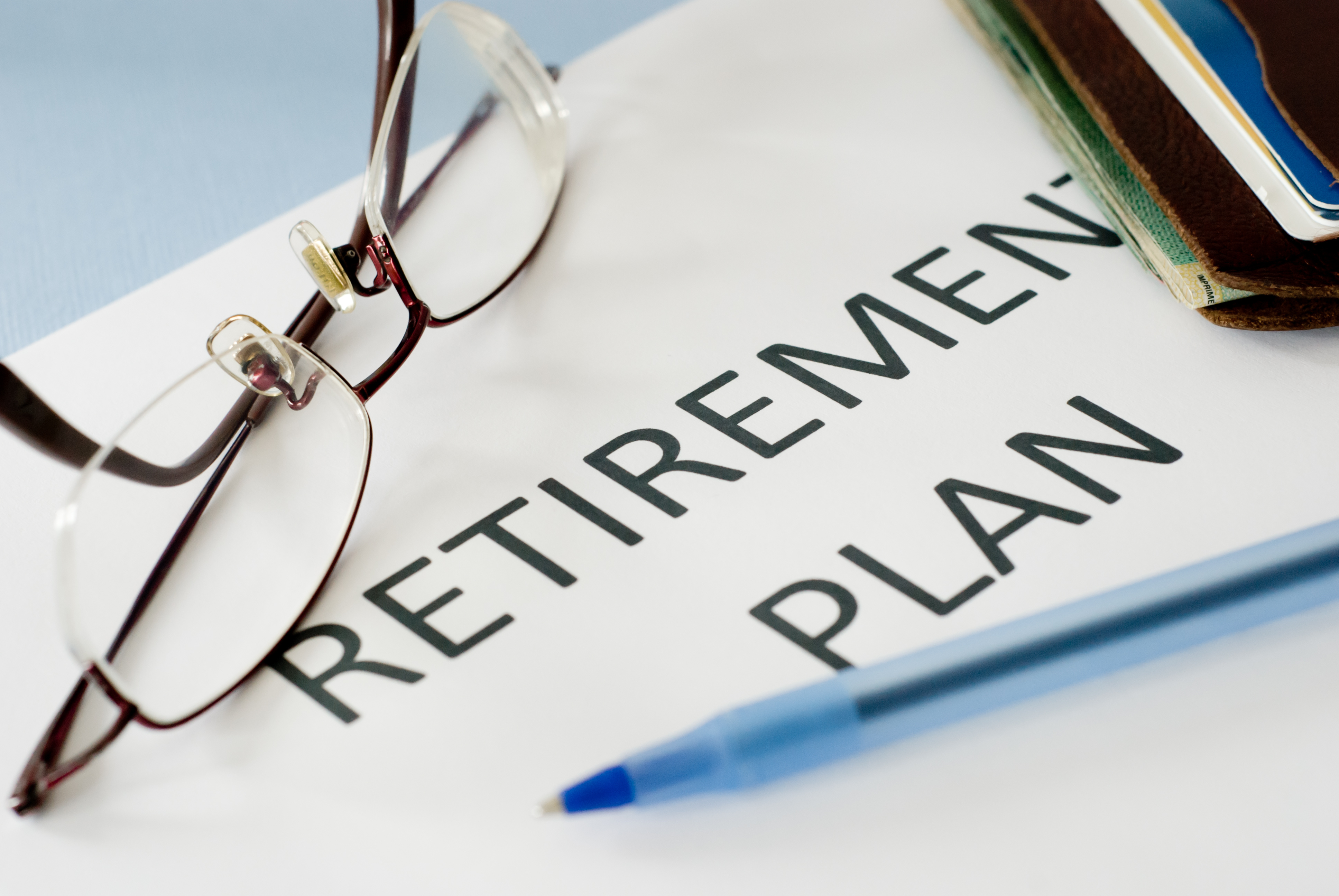 A document with the words 'Retirement Plan' with glasses and a pen