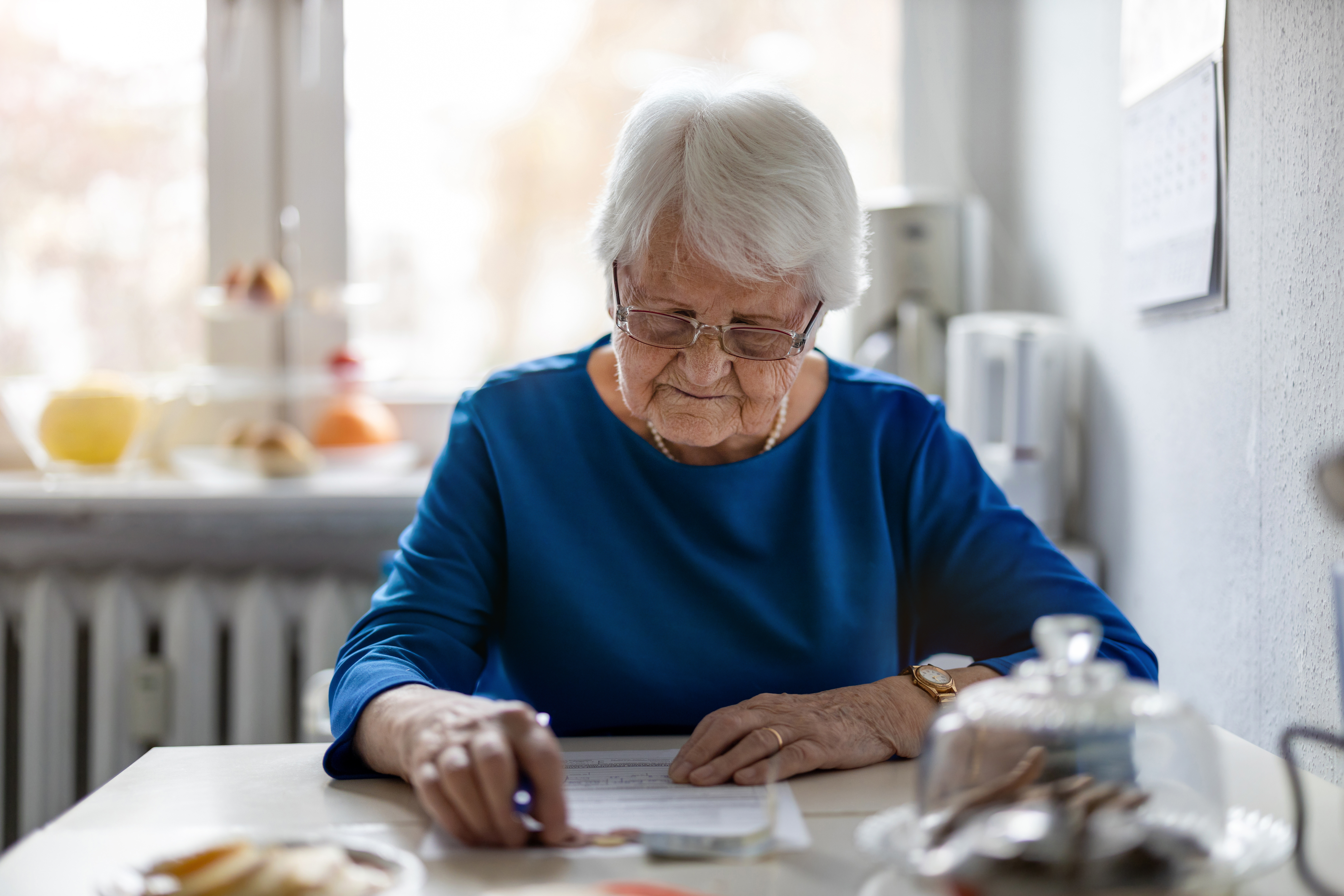 A woman sitting in her kitchen doing paperwork