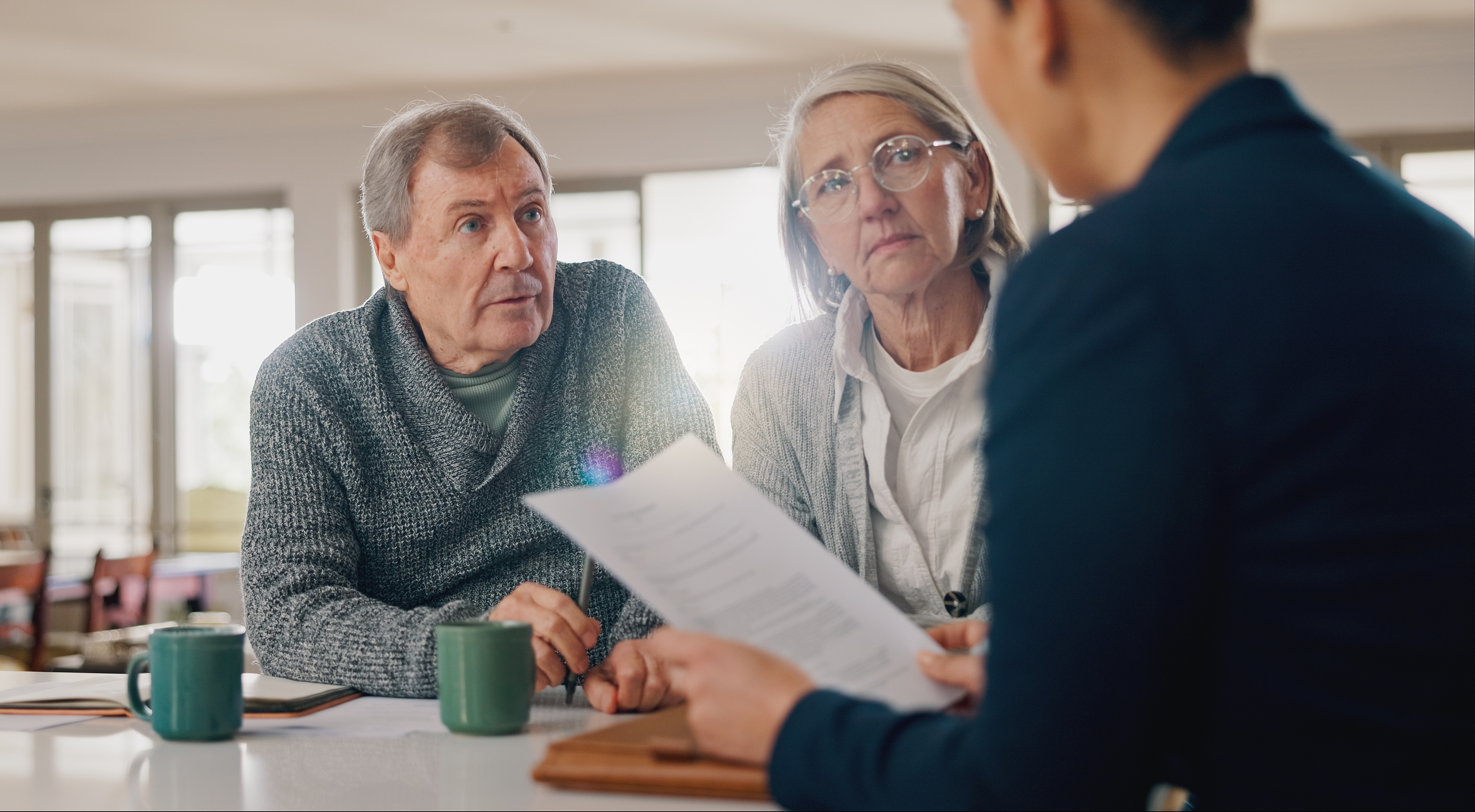 A couple listen to an advisor in a meeting at their home