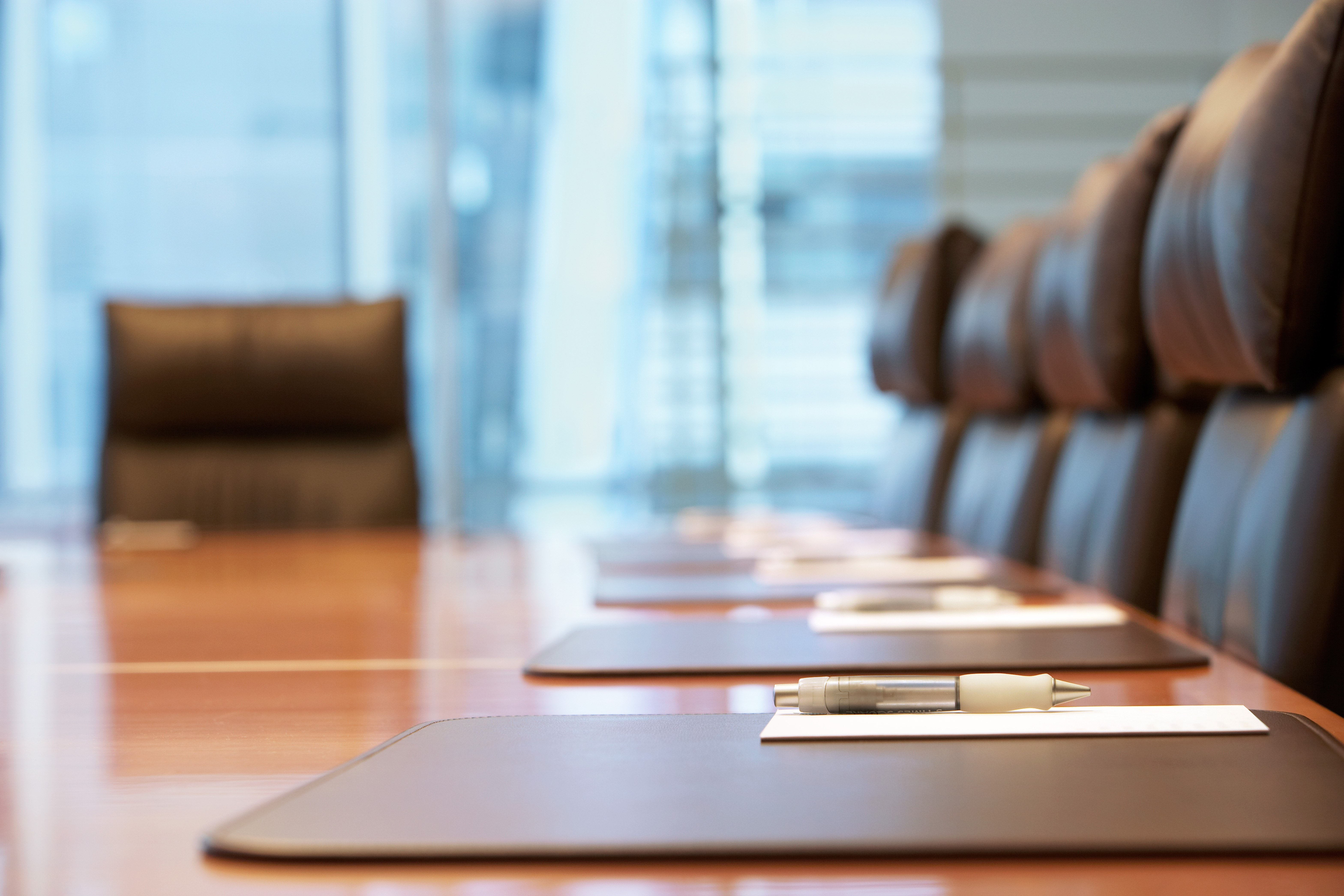 A boardroom with pen, paper and chairs in a row