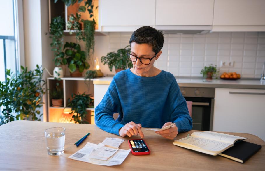 A woman uses a calculator at her kitchen dining table