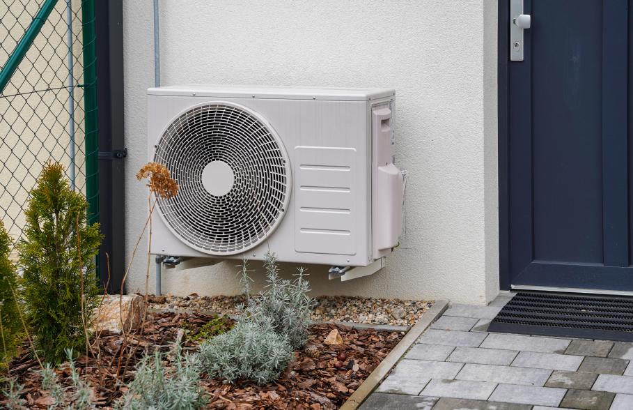Air source heat pump beside front door of a house