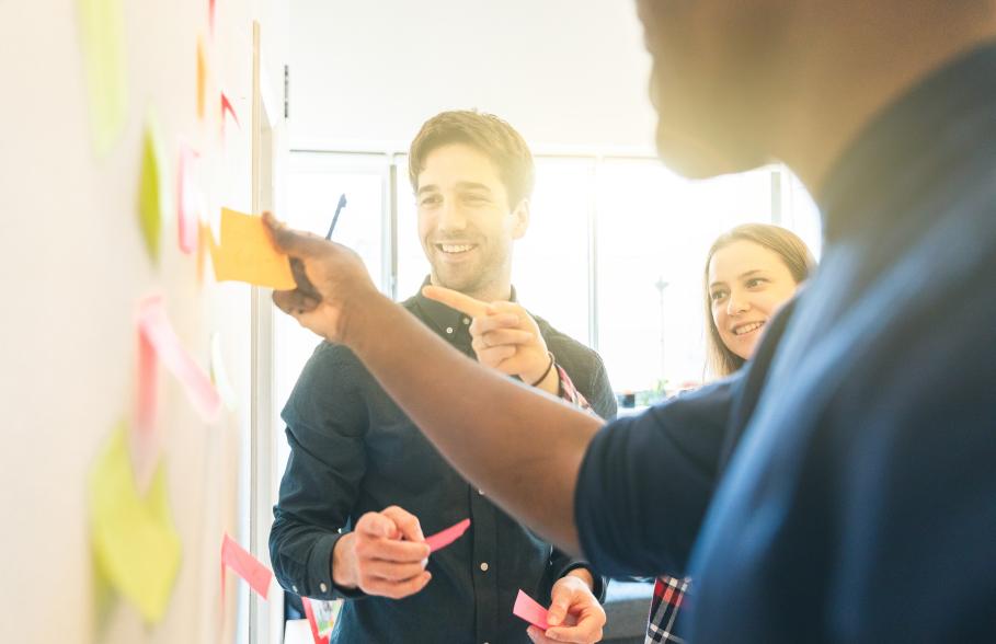 Team members gathering round notes on a wall