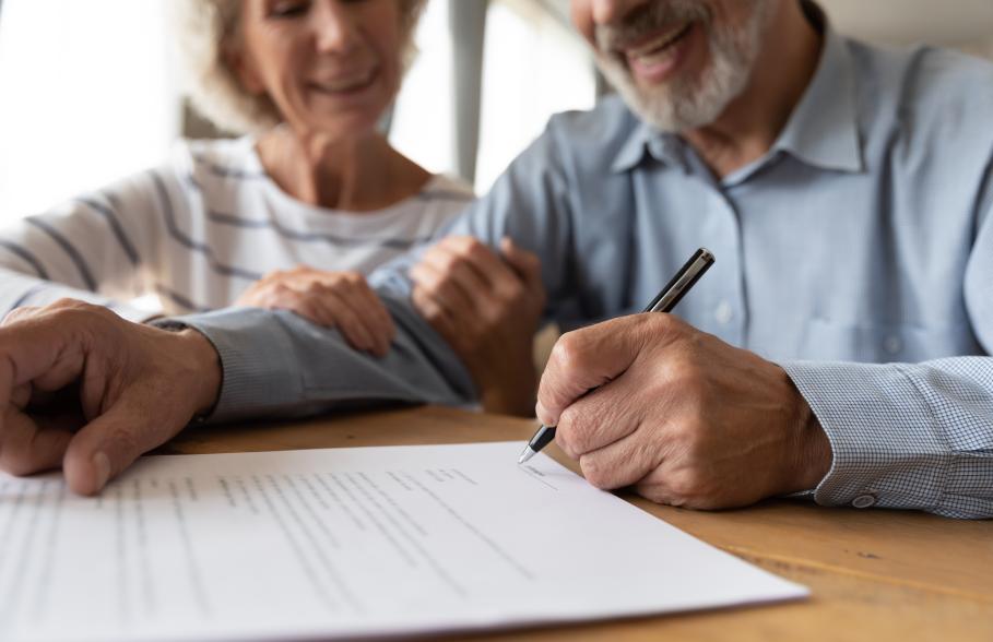 A couple sit at a table signing a document