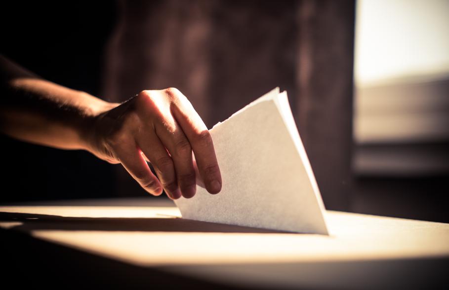 A person placing a voting slip into a ballot box
