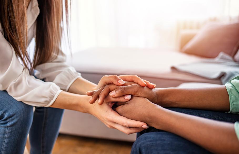 A person supports another person by holding their hands