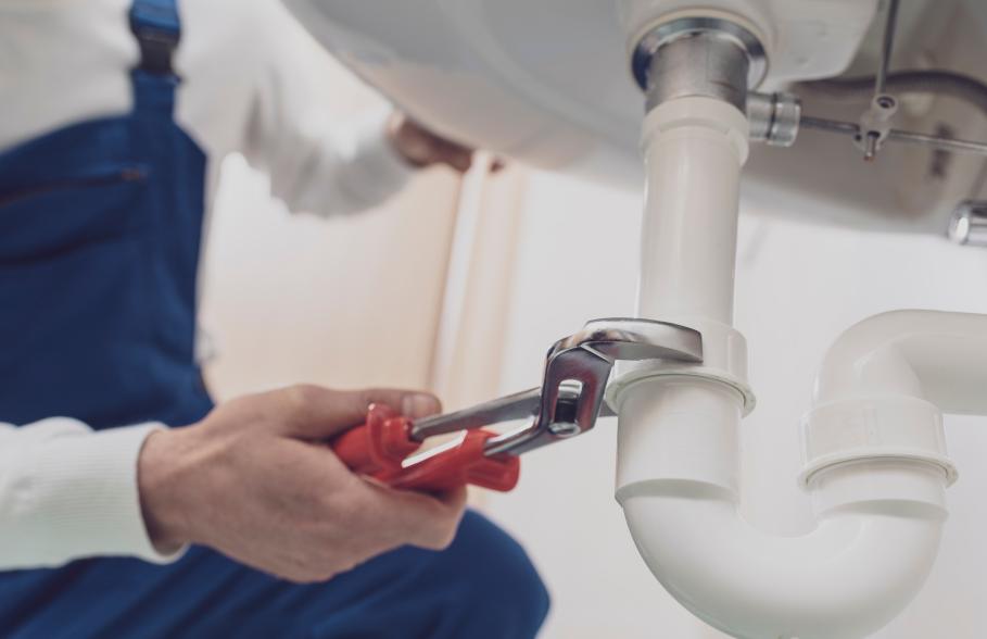A person fixes a u-bend under a sink