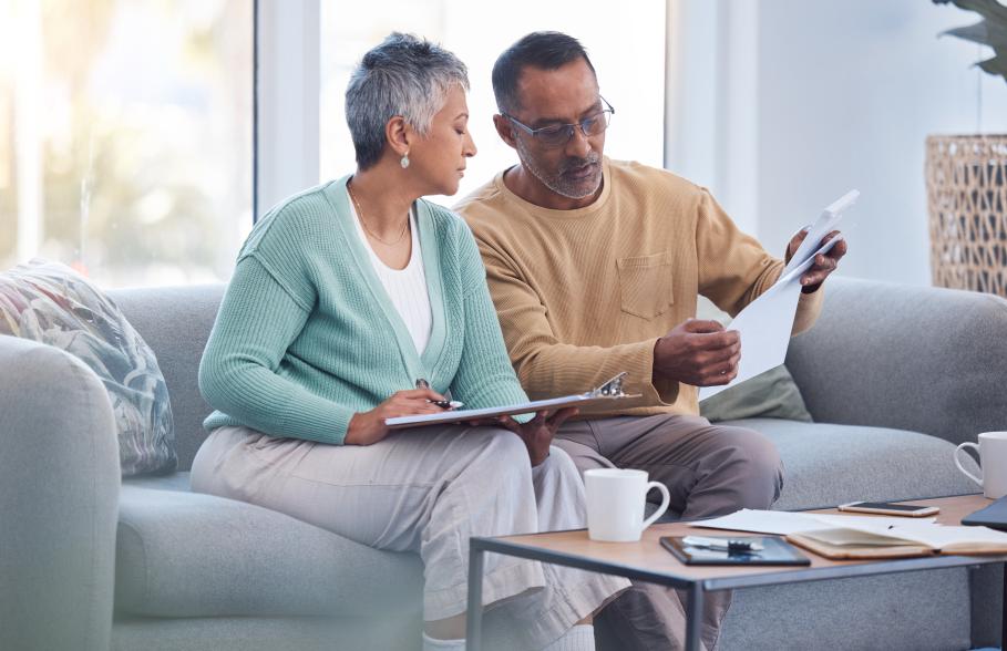 A couple sitting on a sofa reading documents