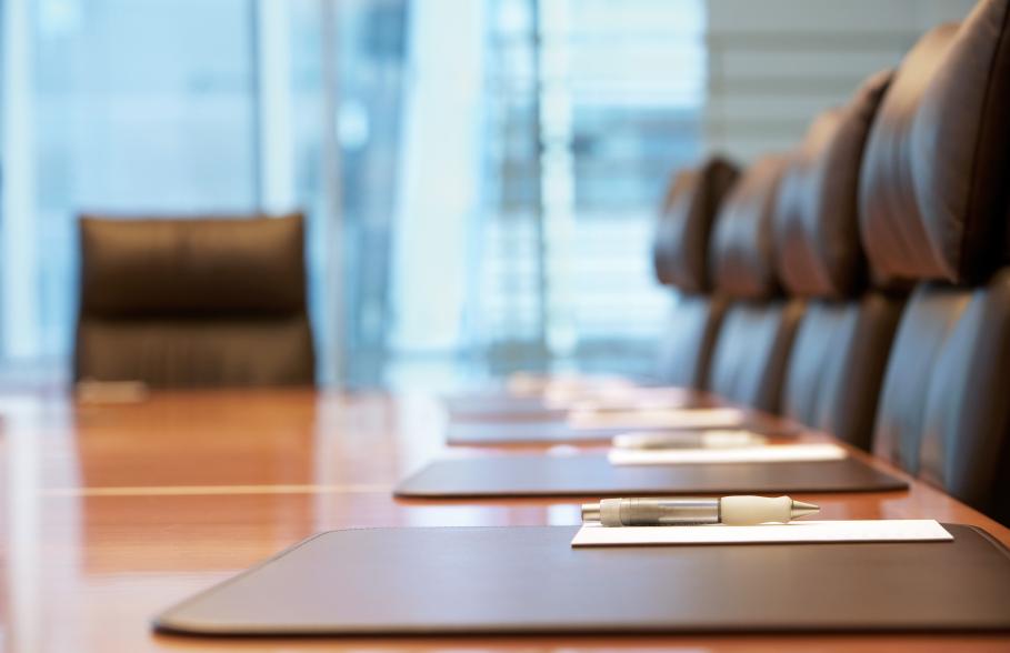 A boardroom with pen, paper and chairs in a row