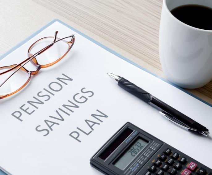 A document with the words 'Pensions Saving Plan' with glasses, pen and calculator