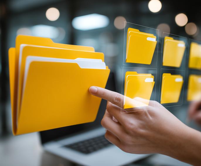 A person points as a graphic of a computer folder against a backdrop of a laptop and office