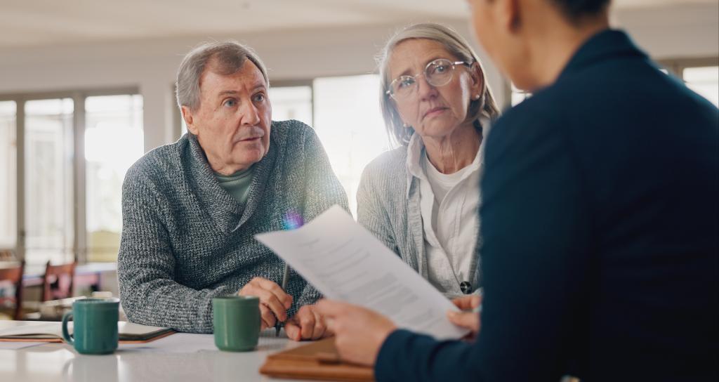A couple listen to an advisor in a meeting at their home